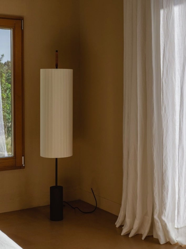 Tall cylindrical floor lamp with dark metal base and fabric shade